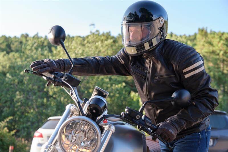 Motorcycle rider wearing safety gear and helmet.