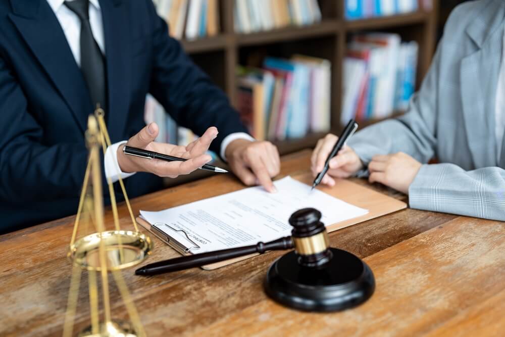 Woman signing settlement in the law office.