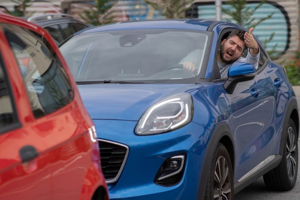 Angry man in the car in the queue yells at the driver in front.