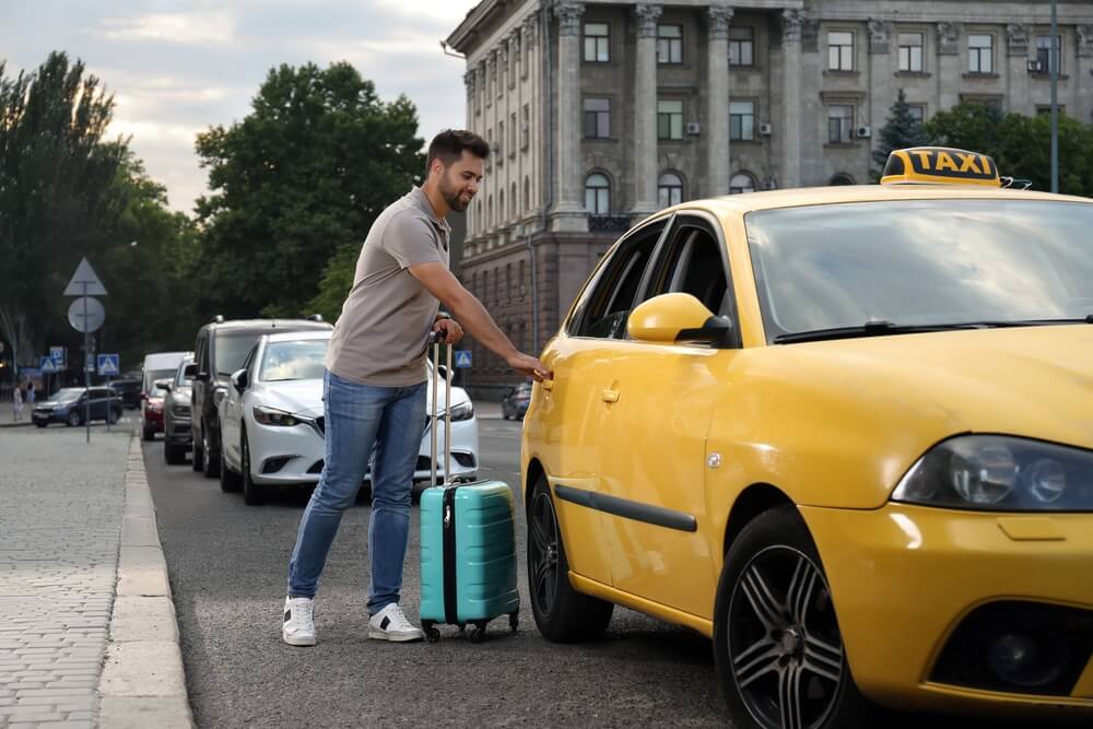Man with suitcase riding a taxi.