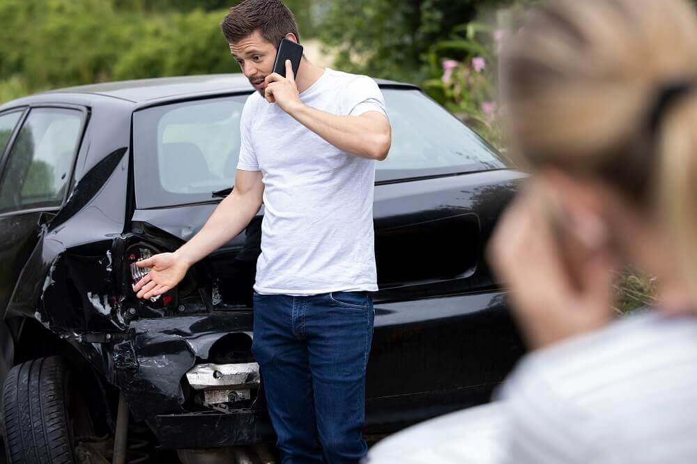 Car rental driver calling insurance to report accident.