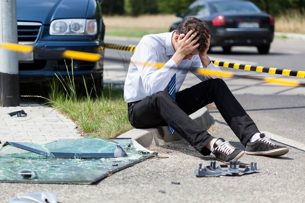 Worried car driver sitting on the side of the road.