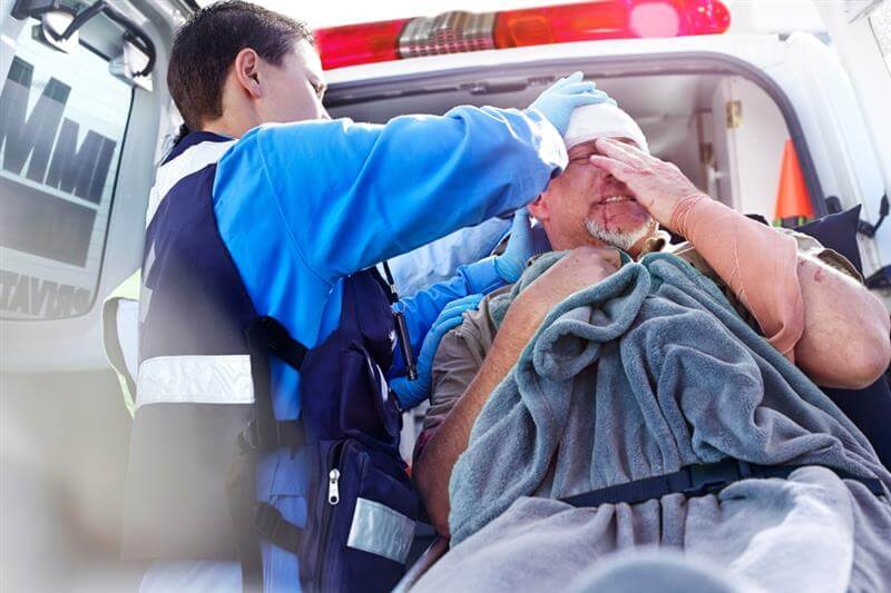 Paramedics rescuing injured driver from car collision.